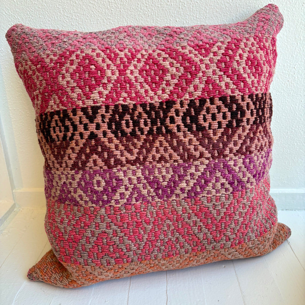 Decorative pillow with shades of pink in a geometric pattern on a white background