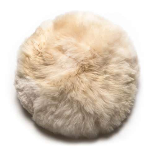 A round beige alpaca wool pillow with a zipper closure.
