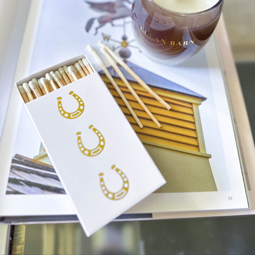 Matches with gold horseshoe design on an open book with candle