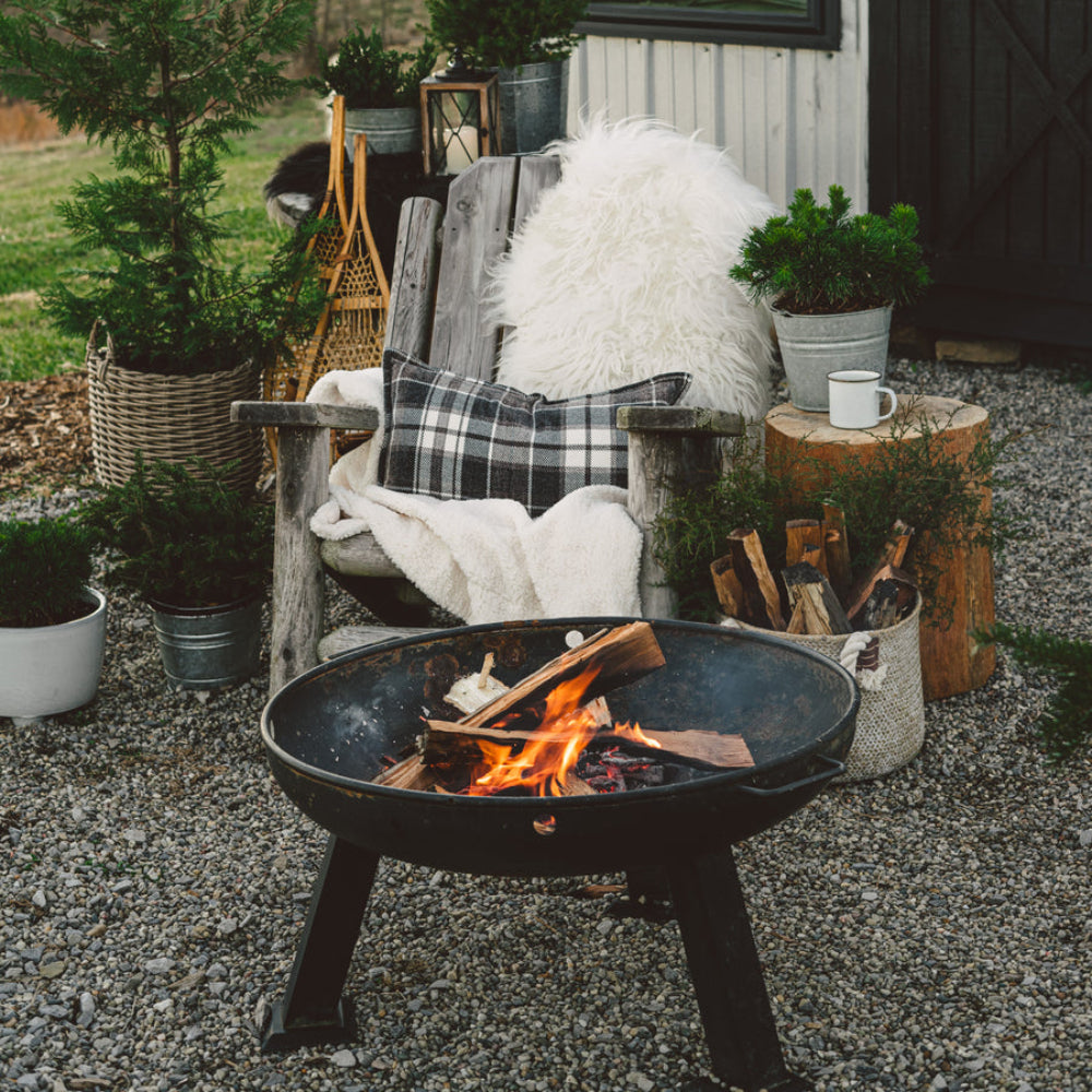 Outdoor setting with a fire pit, chairs, and plants near a white building.
