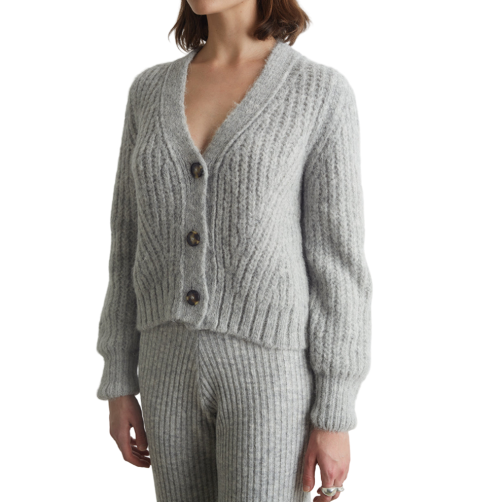 Person wearing a gray ribbed sweater and pants set on a white background