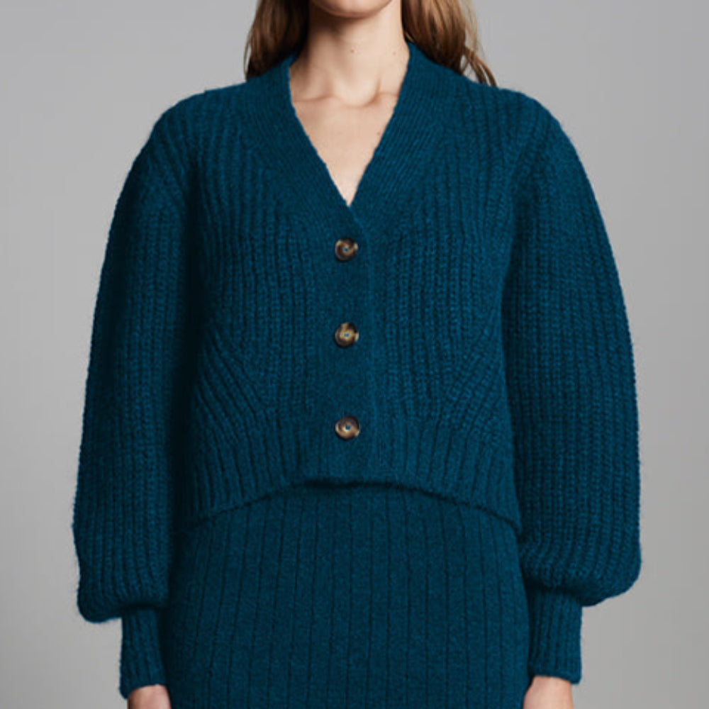 Woman wearing a teal knitted outfit with a gray background