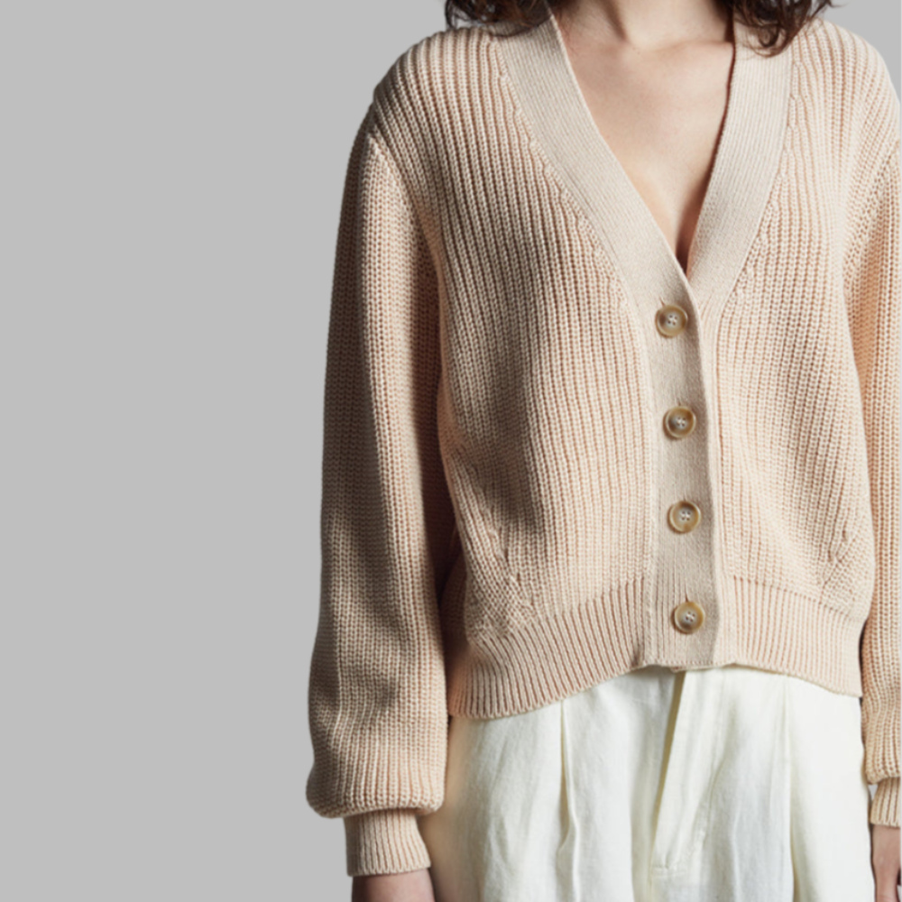 Beige knitted cardigan worn by a person on a plain background