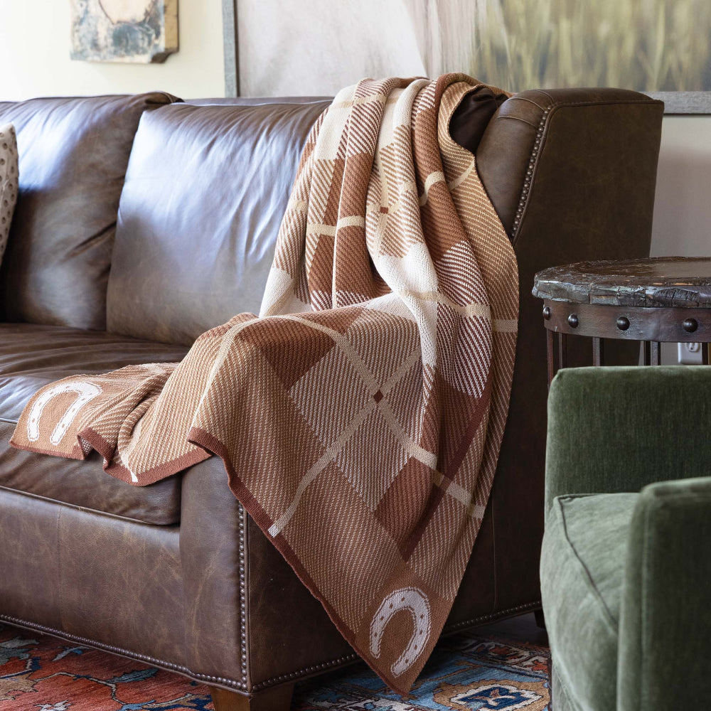 Brown plaid blanket draped over a brown sofa in a living room setting.