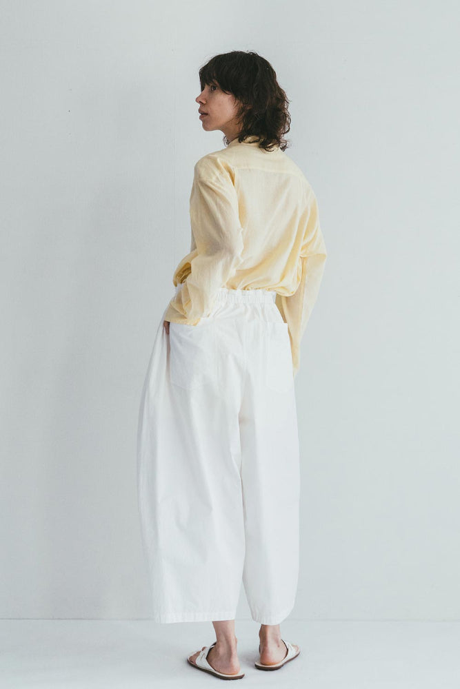 Person wearing a yellow striped shirt and white pants on a plain background
