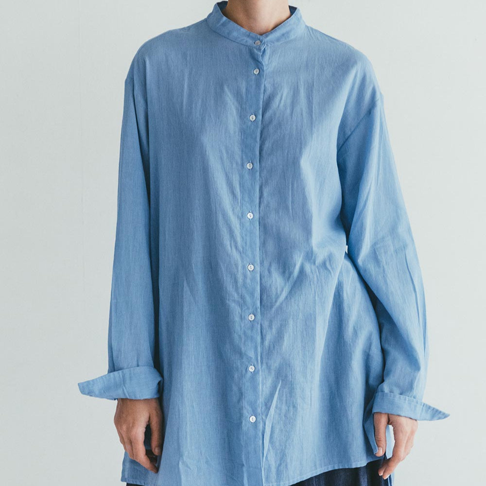 Person wearing a light blue shirt against a plain background