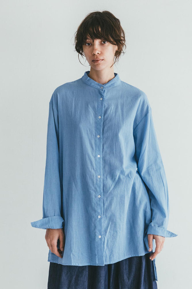 Person wearing a light blue shirt against a plain background