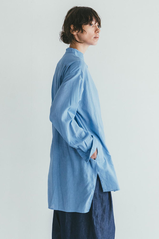 Person wearing a light blue cardigan over a dark blue outfit on a plain background