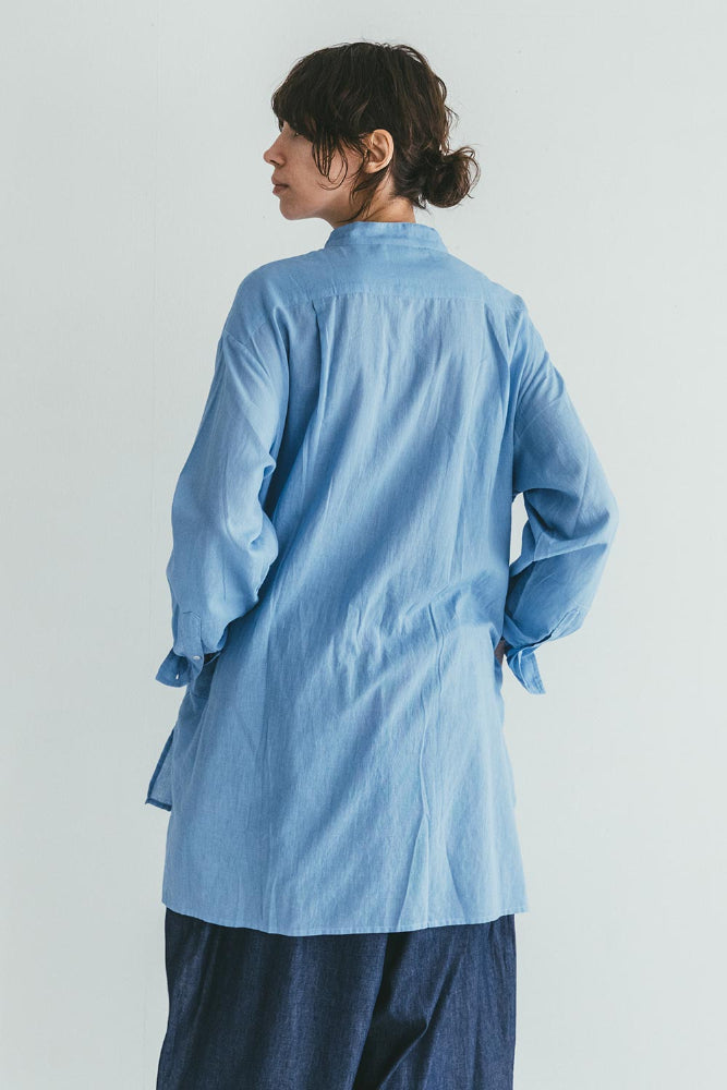Person wearing a light blue shirt against a white background