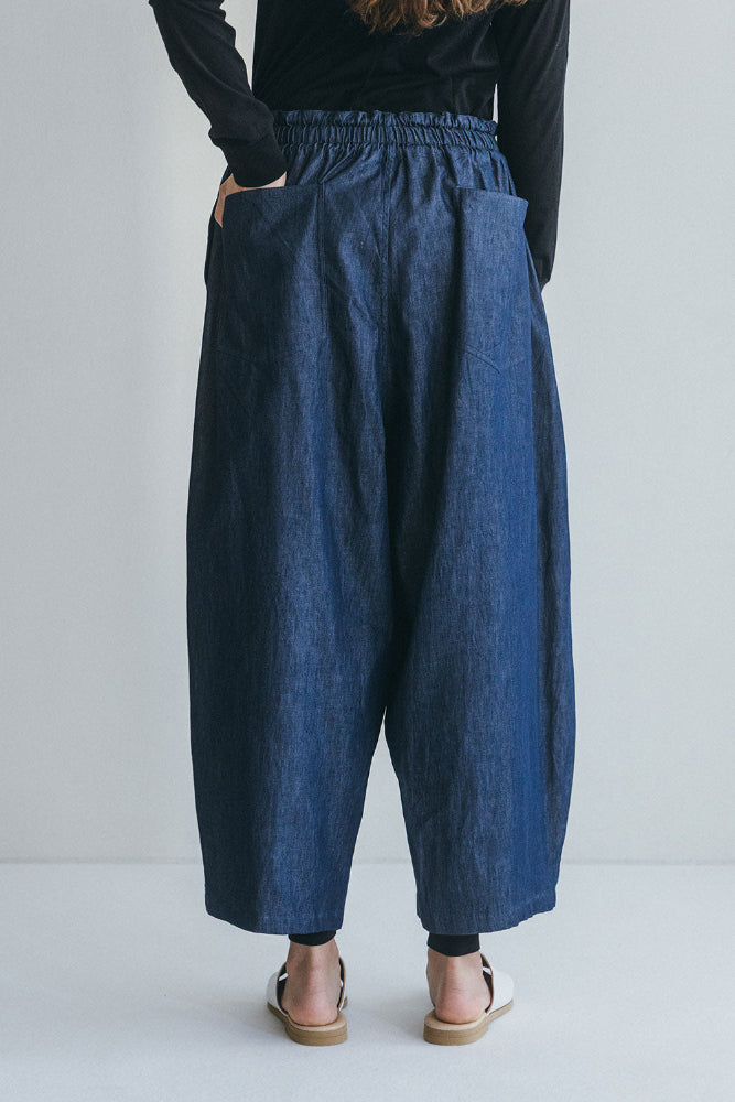 Person wearing blue denim wide leg pants on a plain background