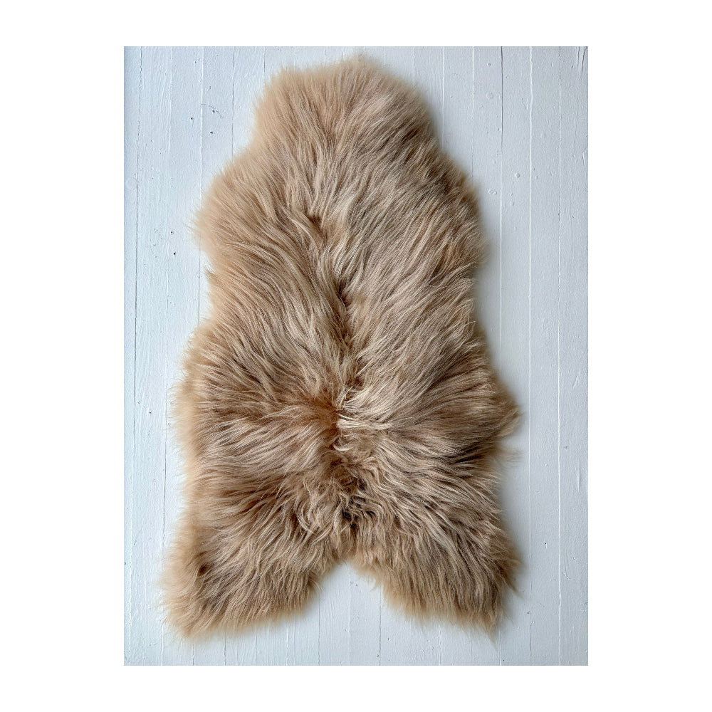light brown sheepskin rug on a white wooden surface