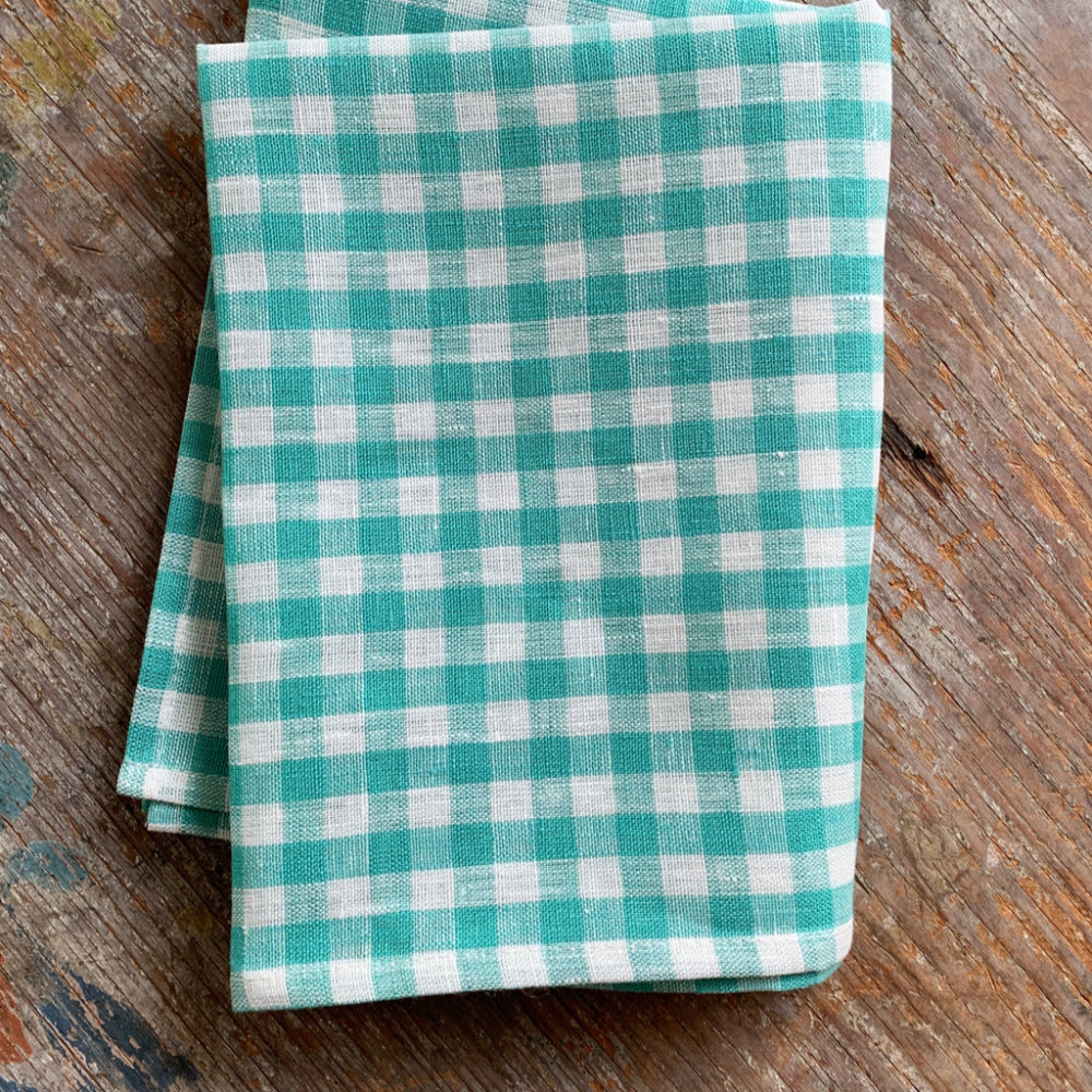 Folded teal and white checkered cloth on a wooden surface