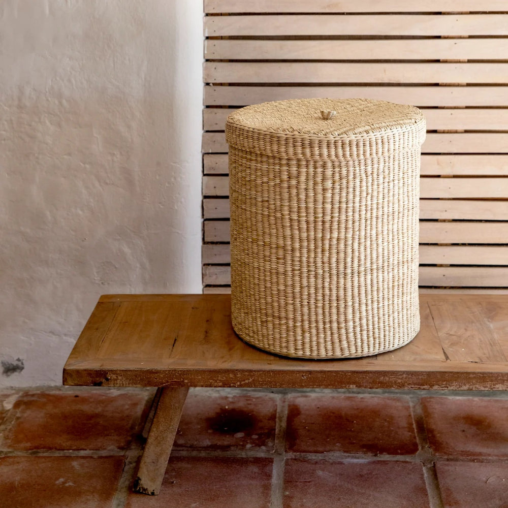 Woven basket on a wooden bench against a slatted wooden wall.