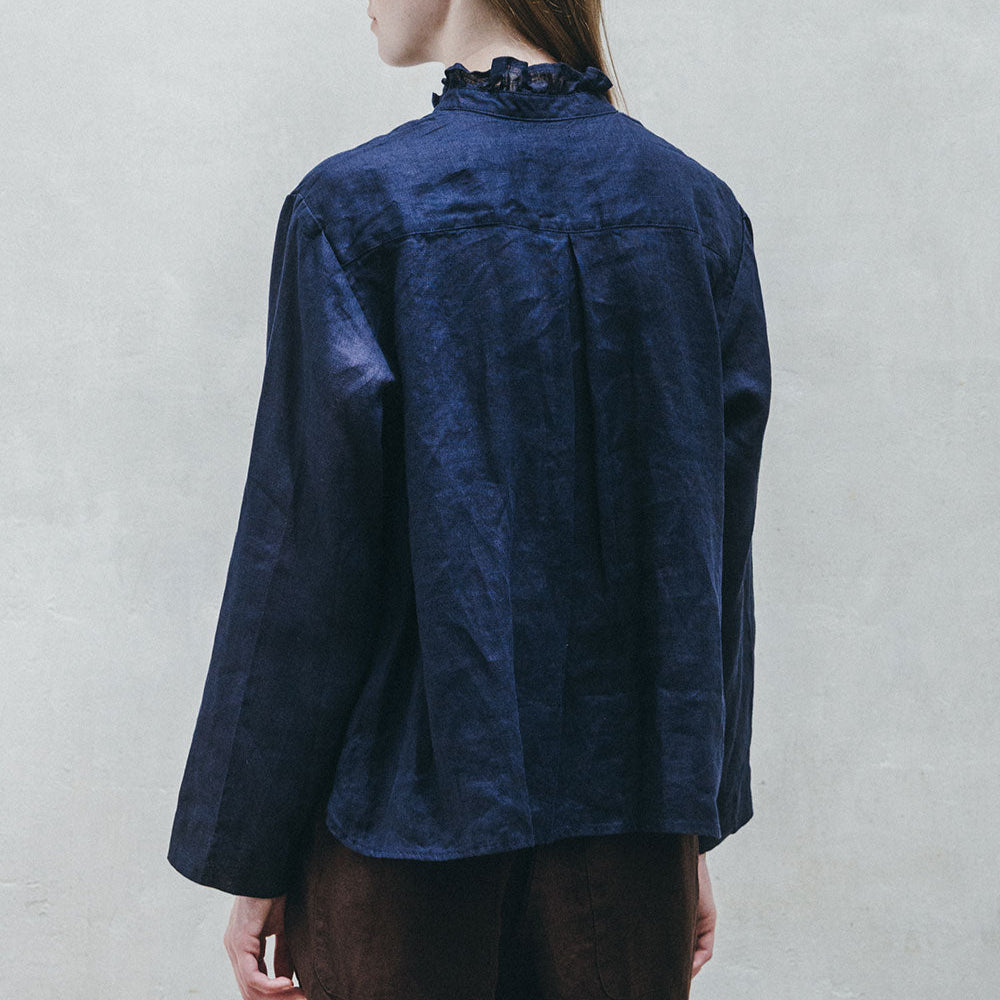 Person wearing a dark blue jacket against a plain background