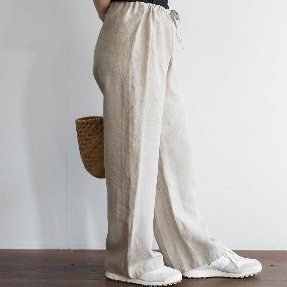 Person wearing beige wide-leg pants and a black top against a plain background