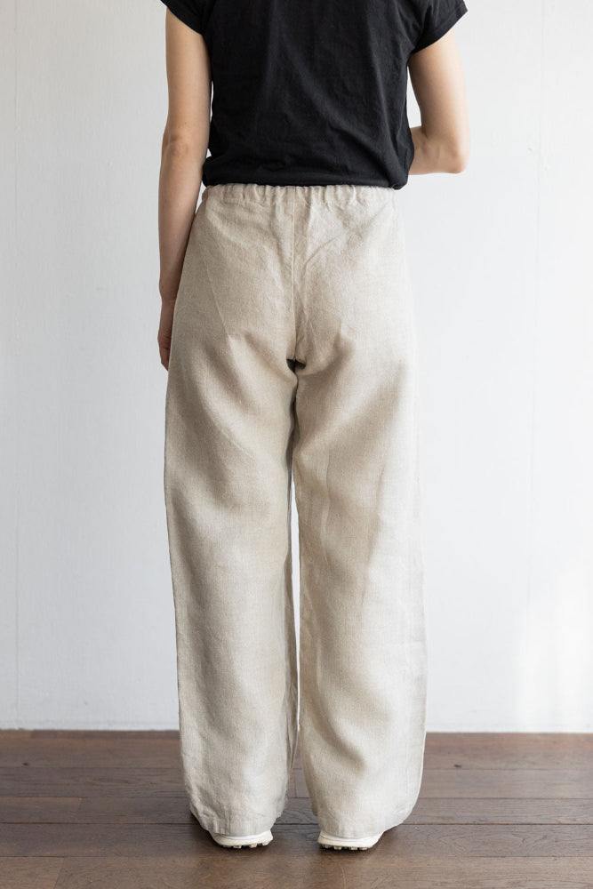 Person wearing beige pants and a black top against a plain background