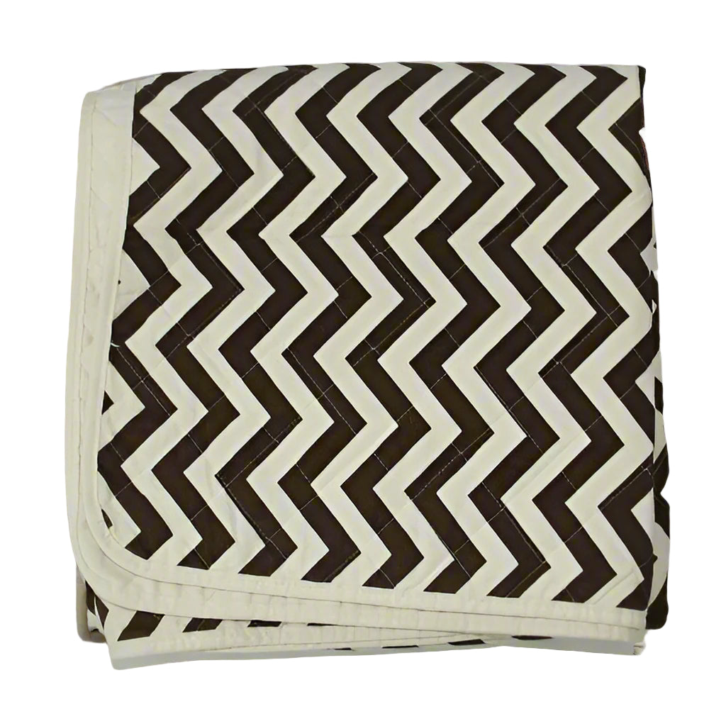 A folded quilted cotton throw blanket with a zig zag geometric pattern in beige and brown colors.