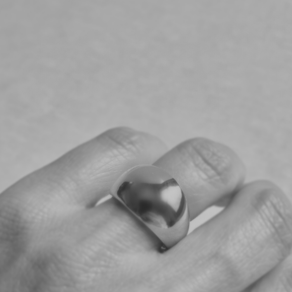 Silver ring on a finger against a gray background