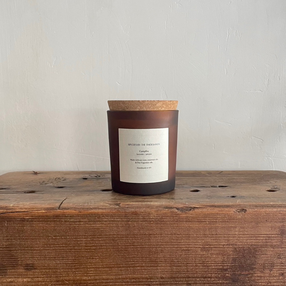 Candle with cork lid on a wooden surface against a light background