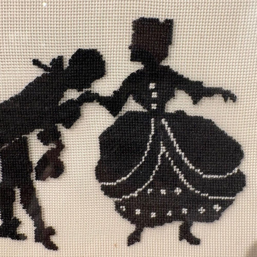 Silhouette of a couple dancing on a needlepoint design.