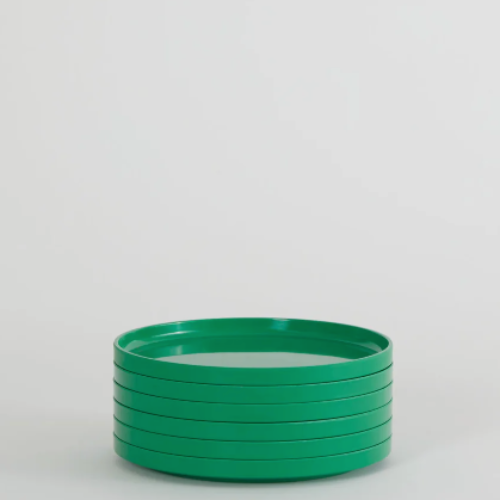 A stack of green Hellerware Max dinnerware plates on a white background.