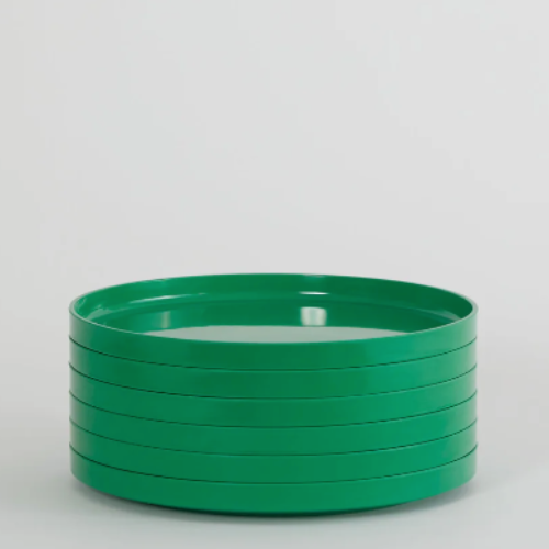 Stacked green Hellerware Max ceramic dinner plates on a neutral background.