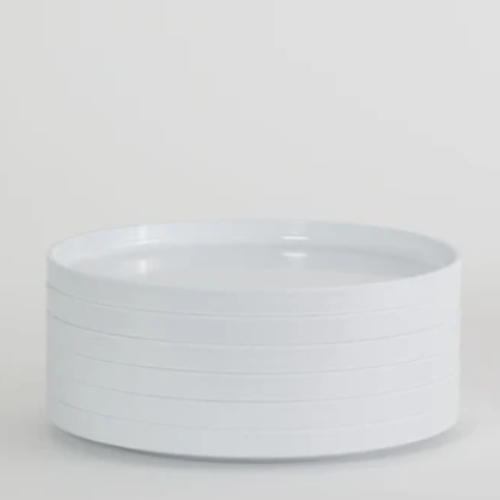 Stacked white Hellerware ceramic dinner plates on a neutral background.