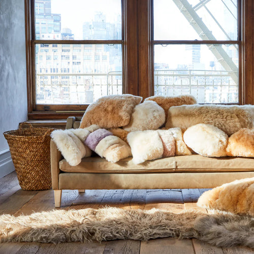 sofa covered with Fur throw pillows in a room with large windows overlooking an city landscape