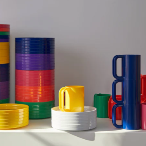 Colorful Hellerware Max mugs and plates on a white surface with a gray background