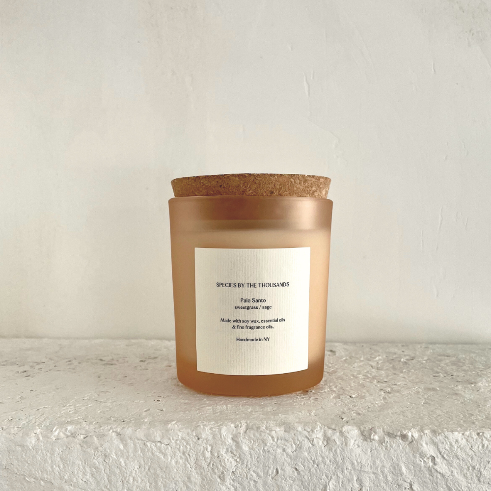 Candle with cork lid on a textured surface and light background