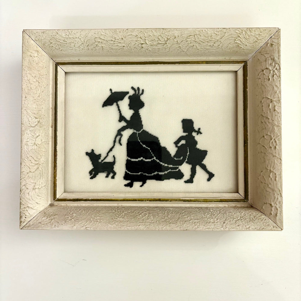 Framed silhouette art of a lady with a dog and child on a white background