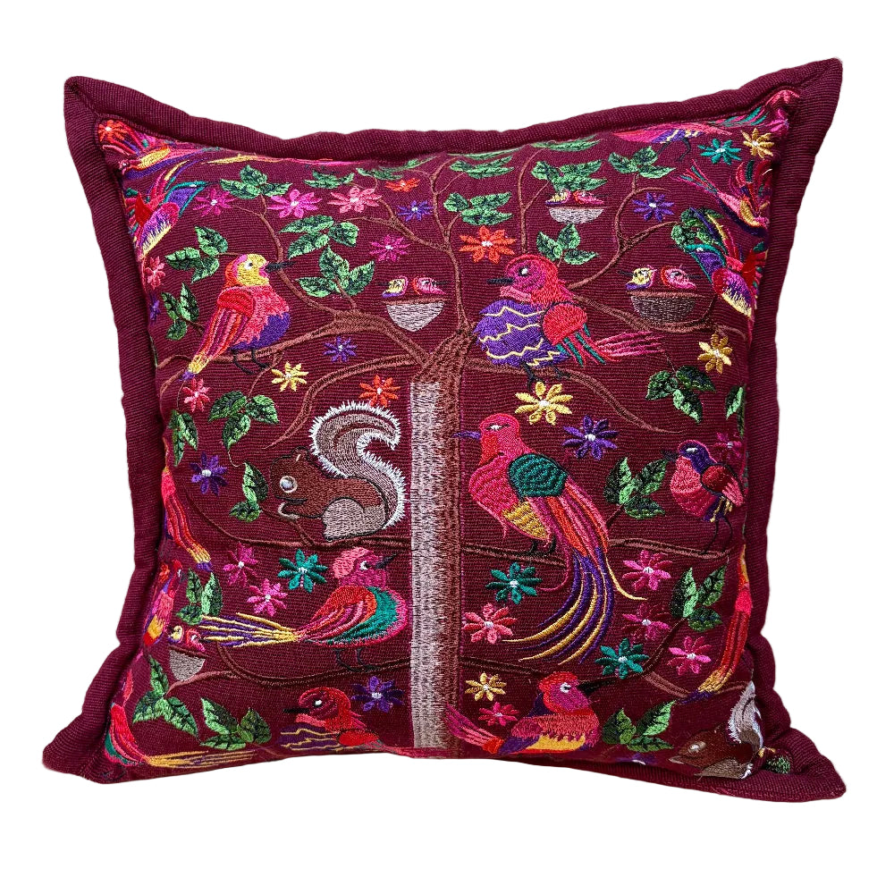 A square decorative throw pillow with a deep burgundy base, featuring vibrant multicolor embroidery of birds, a squirrel, flowers, and a tree on the front