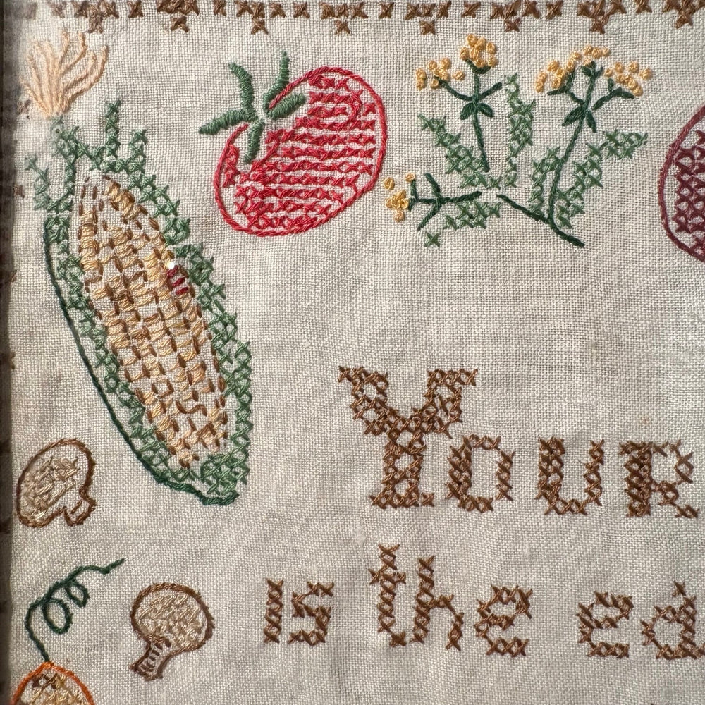 Embroidered fabric with corn, apples, and text on a beige background
