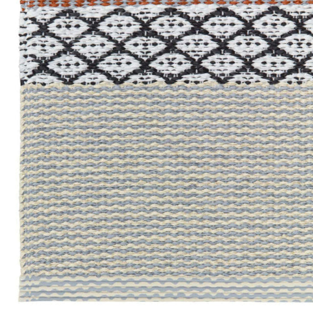 Close up of a woven PVC floor mat with a geometric pattern in gray, beige, and brown colors.